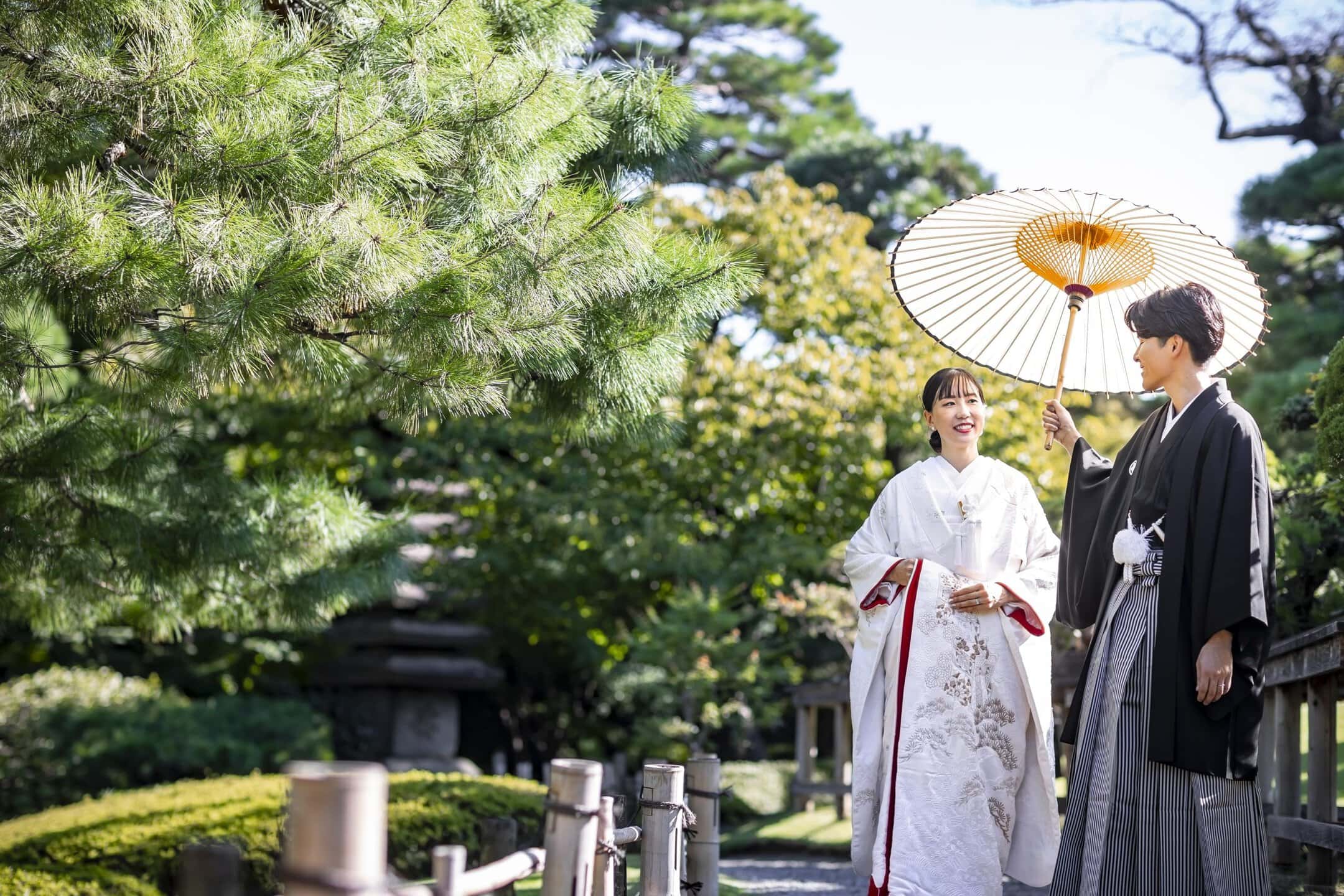 伝統的な和装のカップルが八芳園の庭園で桜の季節にロケーションフォトを楽しむ様子.