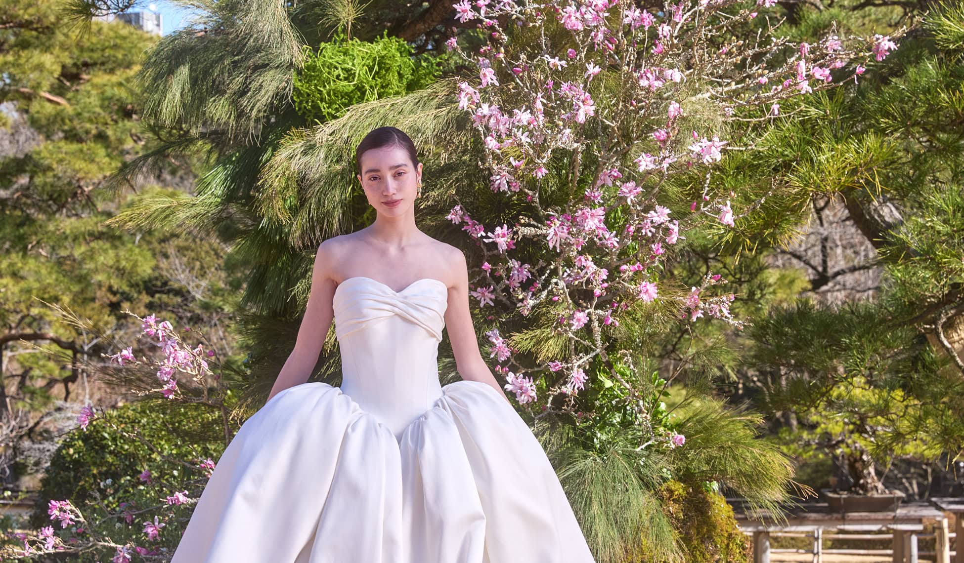 白いウェディングドレスを着た花の背景の女性の画像, 日本の結婚式場の衣裳写真, ハッポー園の美しい庭園での撮影.