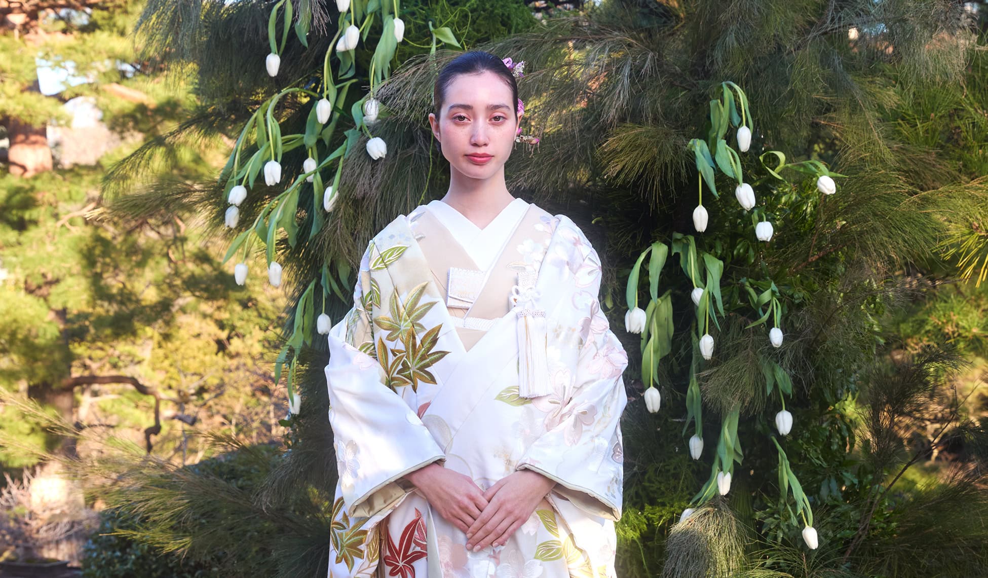 伝統的な白無垢の衣装を着た女性が自然の背景の前でポーズをとる日本の結婚式シーン.
