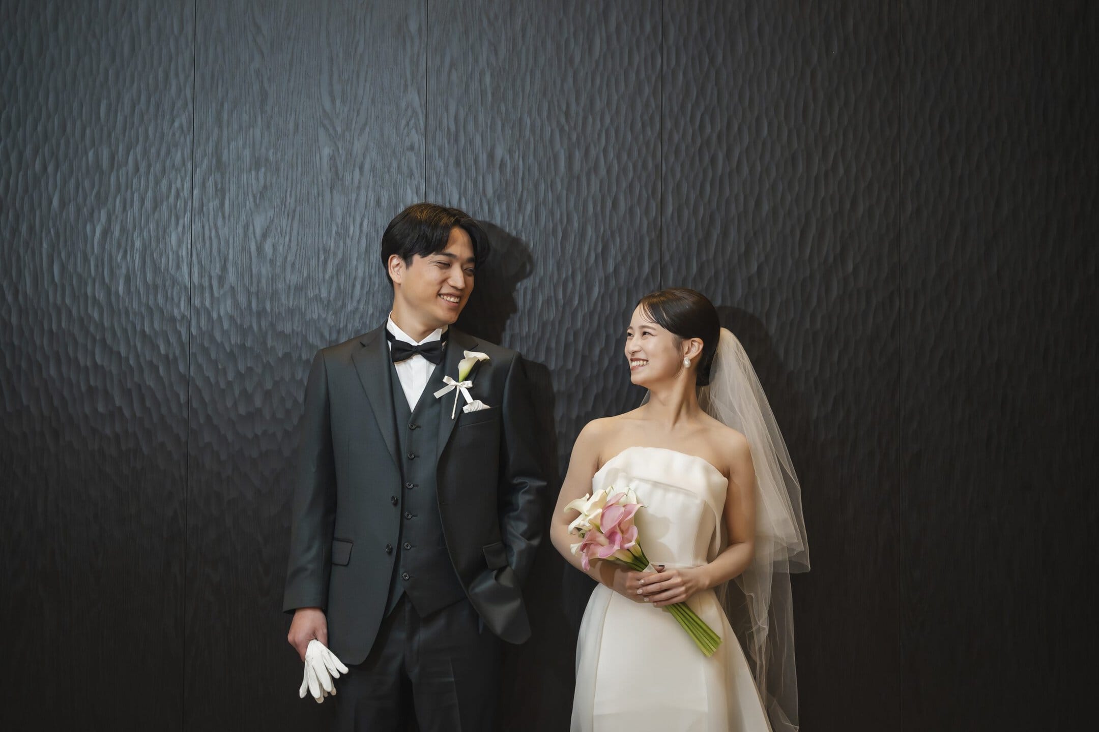 A portrait of the bride and groom, capturing their smiles and happy moments, in their wedding attire and holding bouquets.