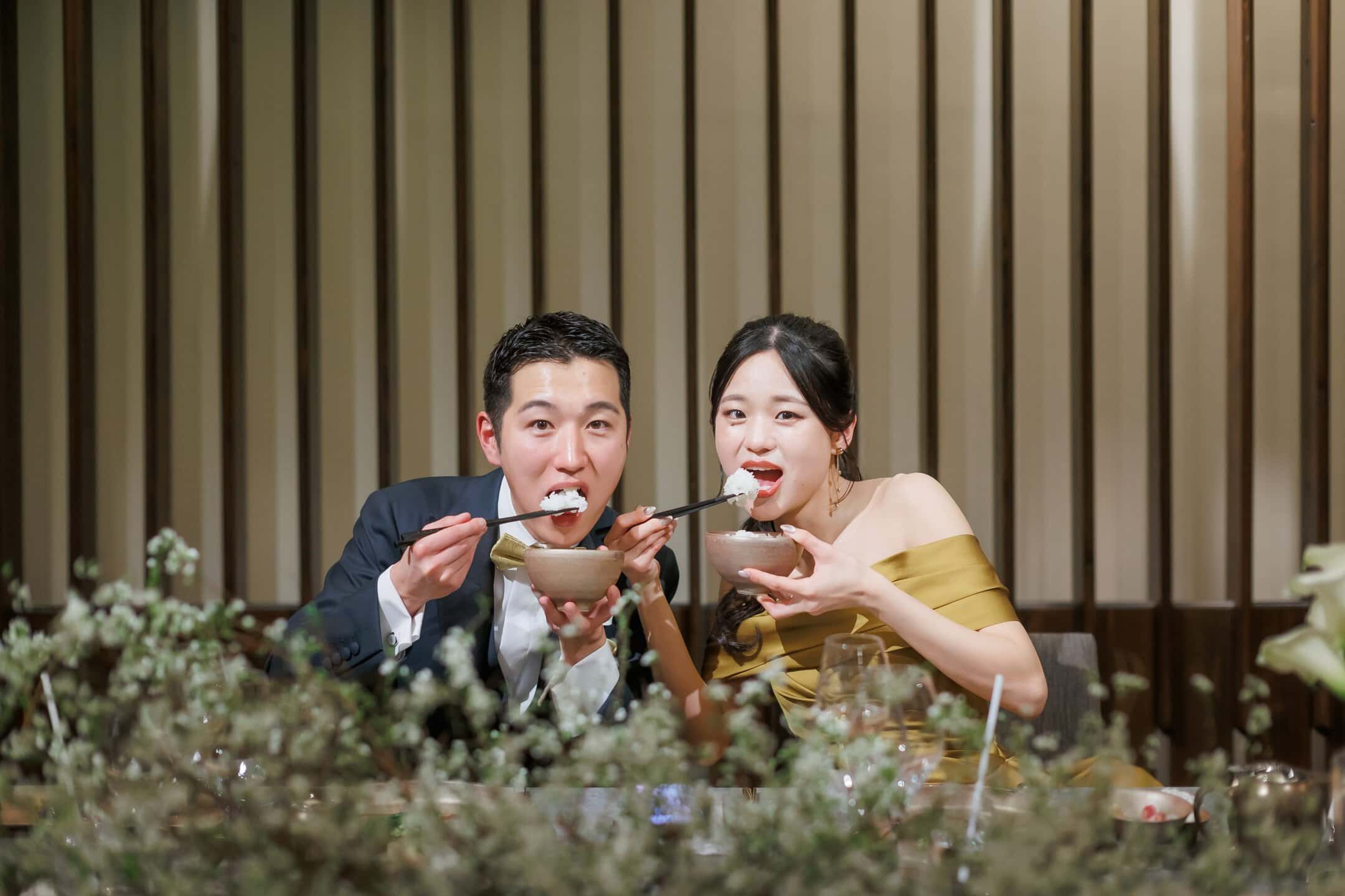 新郎新婦が和風のレストランでお箸を使ってデザートを楽しむ幸せな結婚式のシーン.