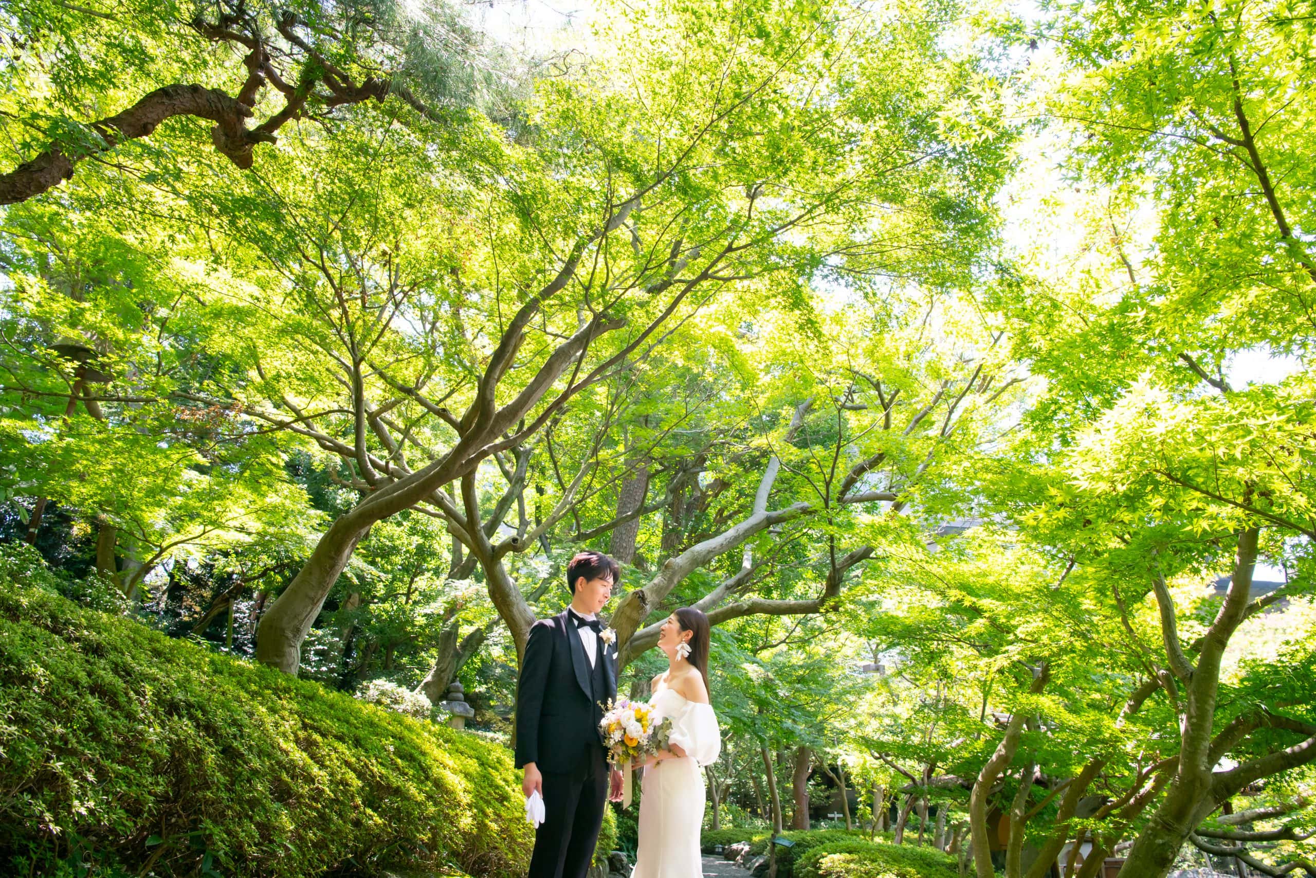 八芳園の庭園での結婚式の新郎新婦と緑豊かな木々の風景.