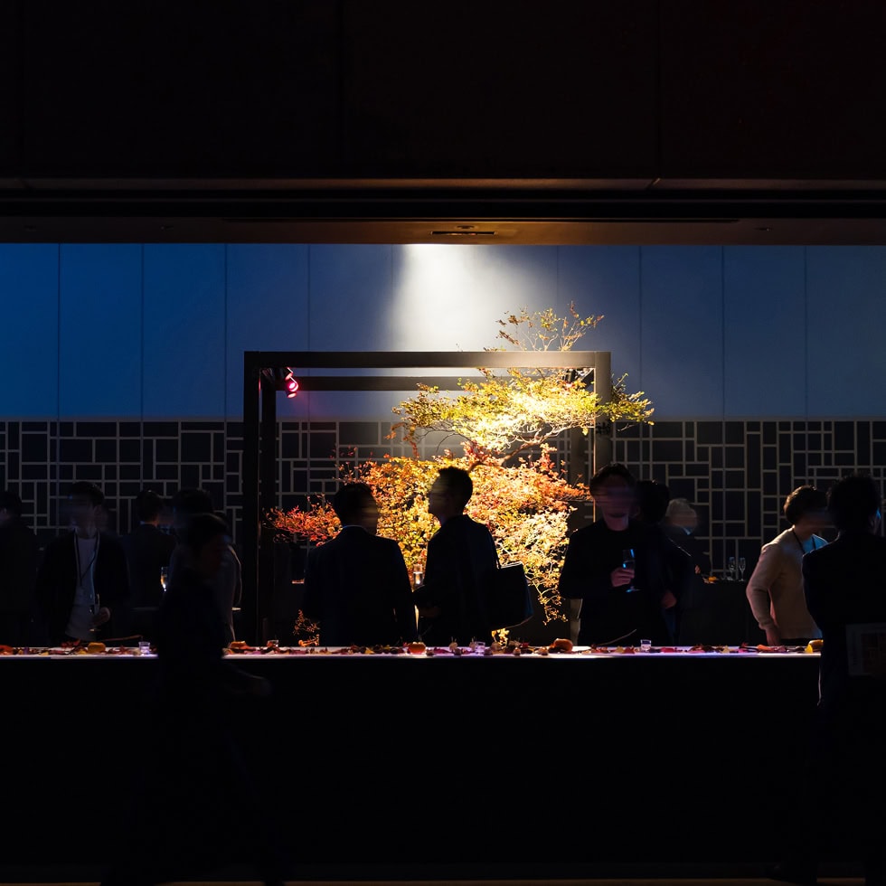 和風の宴会会場で秋の紅葉を背景にした美しい装飾とゲストの交流風景.