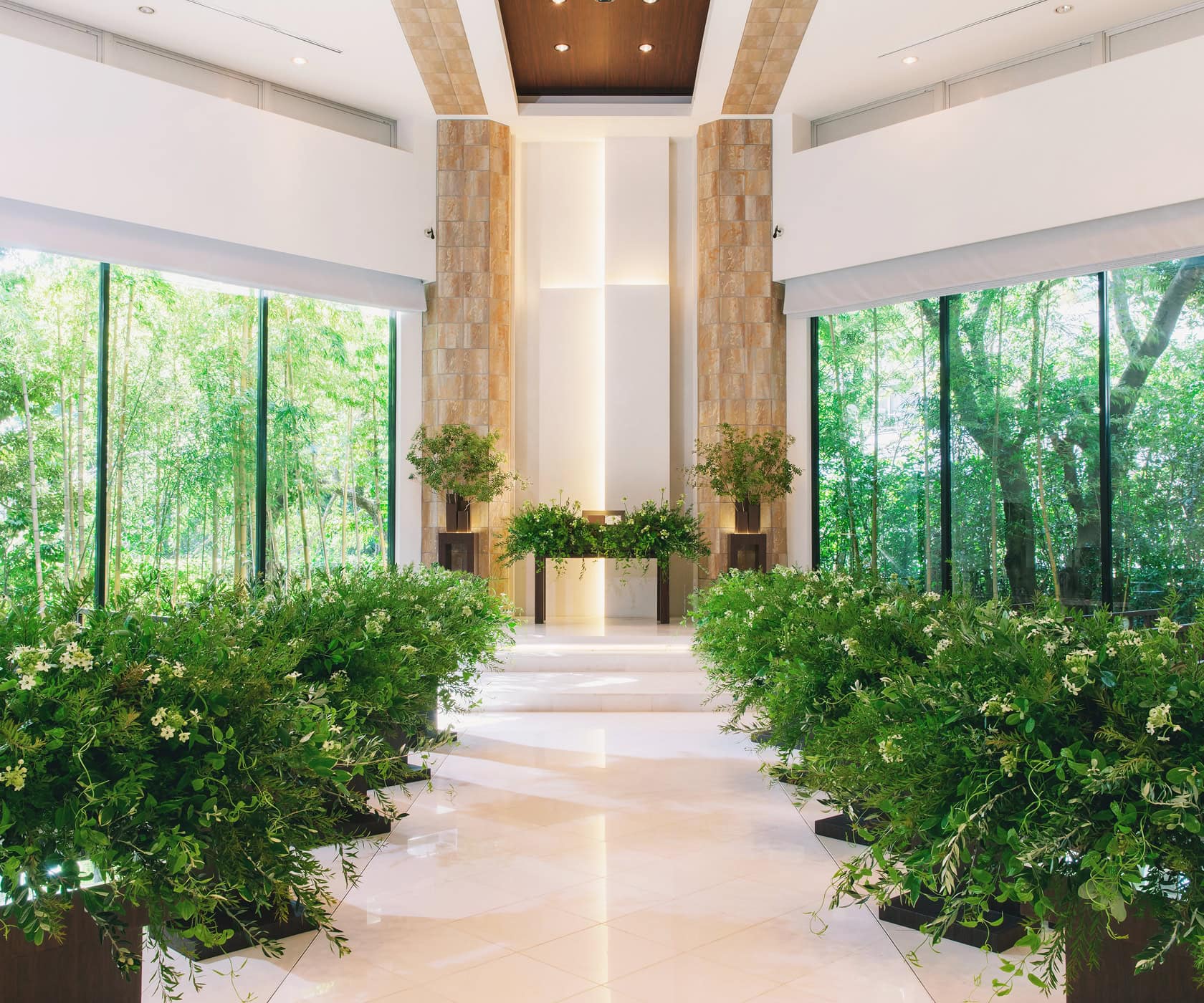 A modern wedding venue surrounded by lush greenery, featuring beautiful interior decor and stunning views from its large windows.